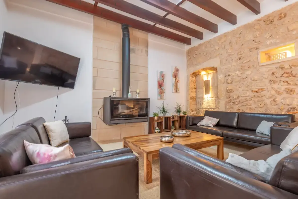 A living room with dark seating around a wooden coffee table and fireplace.