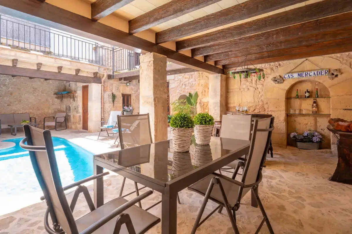 A covered patio dining area overlooks a swimming pool.
