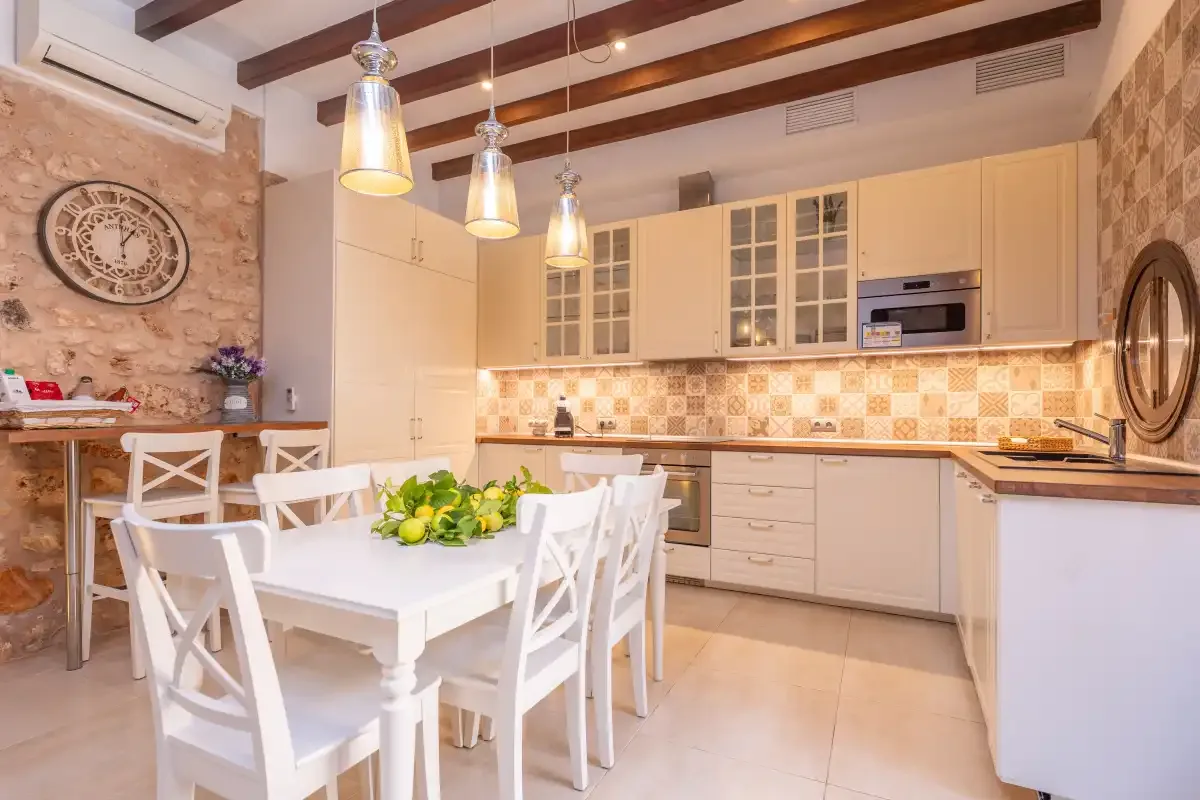 A kitchen and dining area with white seating and pendant lights.