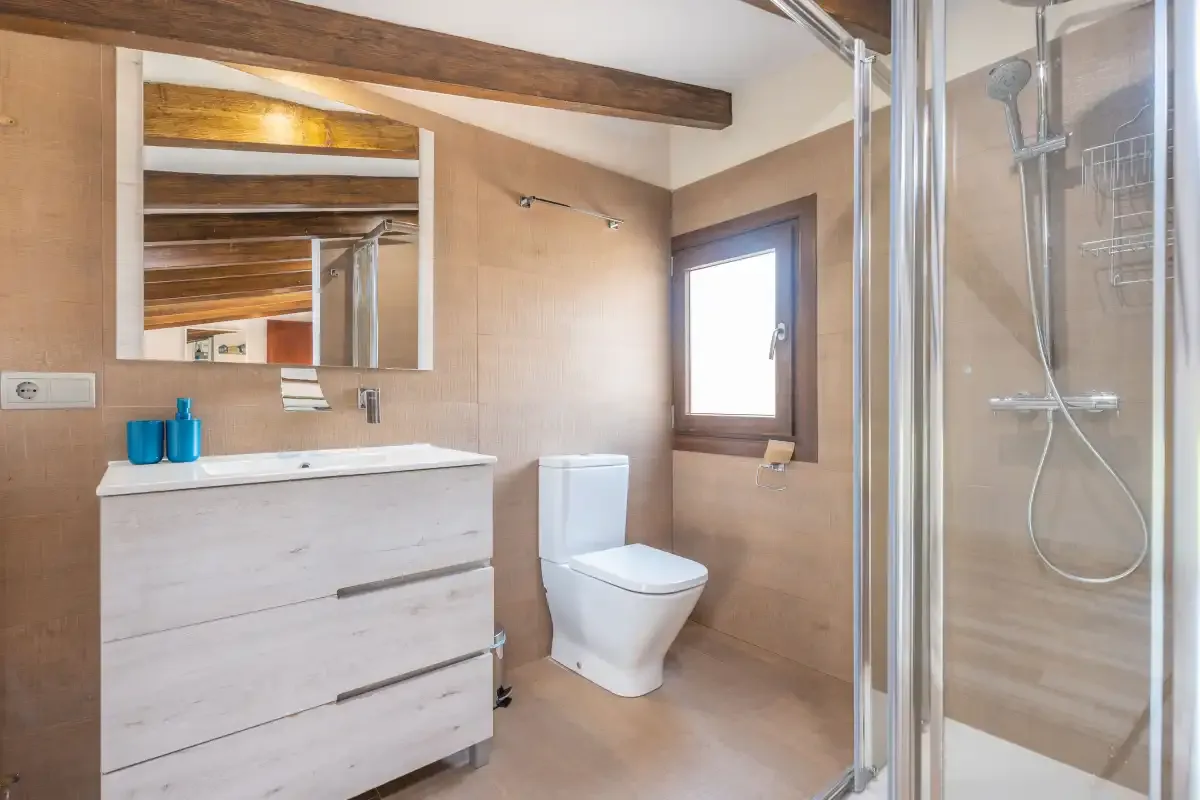 A bathroom with a vanity, toilet, and glass-enclosed shower.