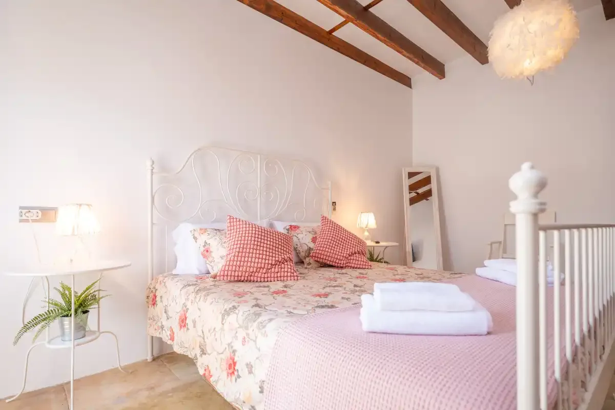 A bedroom with a floral bedspread and folded towels on the bed.