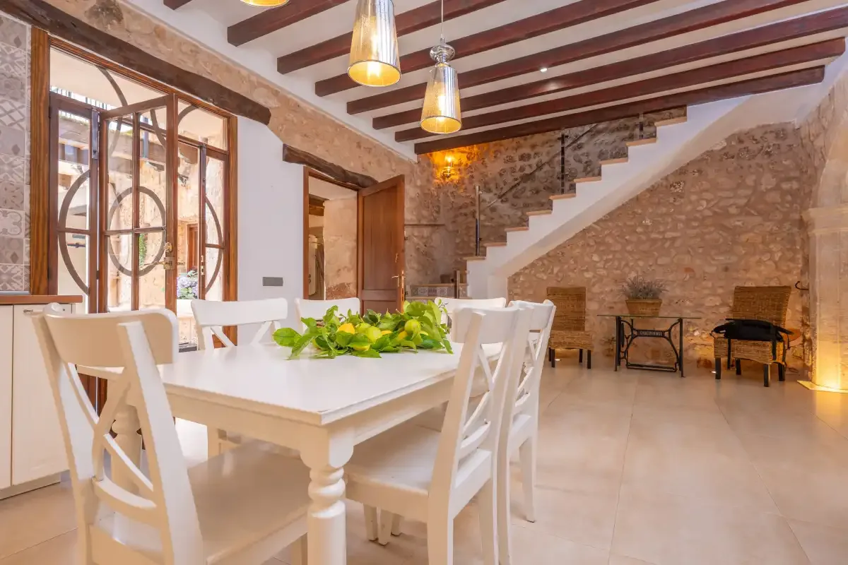 A dining area with a white table and chairs beneath exposed ceiling beams.