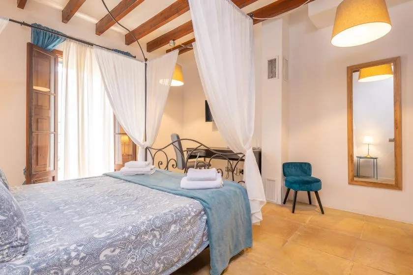 A bedroom with a canopied bed and a blue upholstered chair.