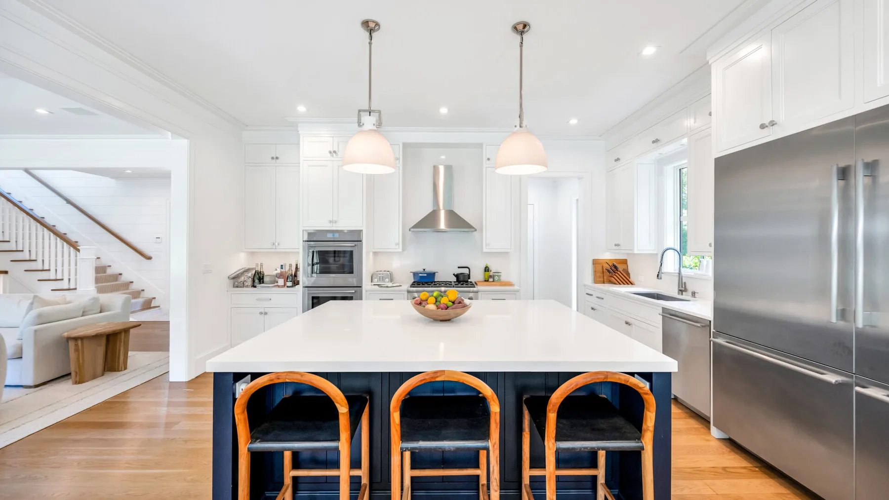 Una cocina luminosa con una isla grande, asientos de barra y electrodomésticos de acero inoxidable.