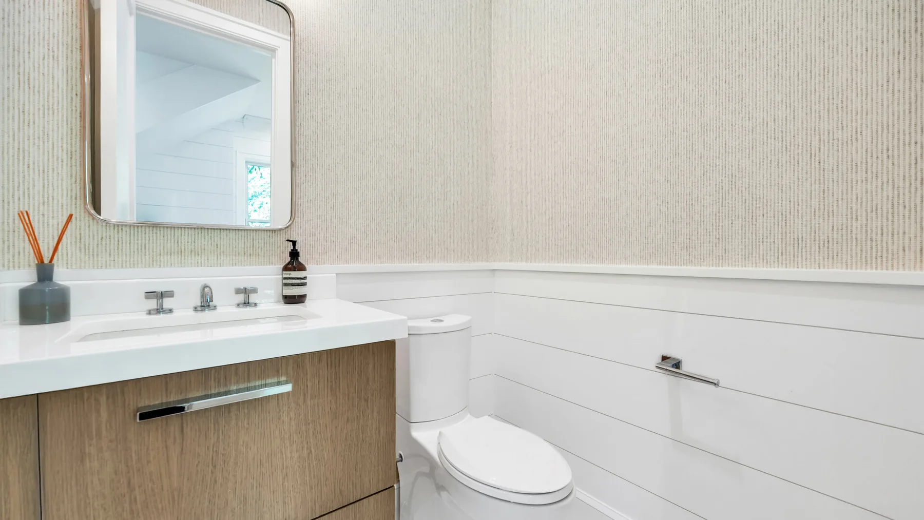 Un tocador de baño con espejo e inodoro.