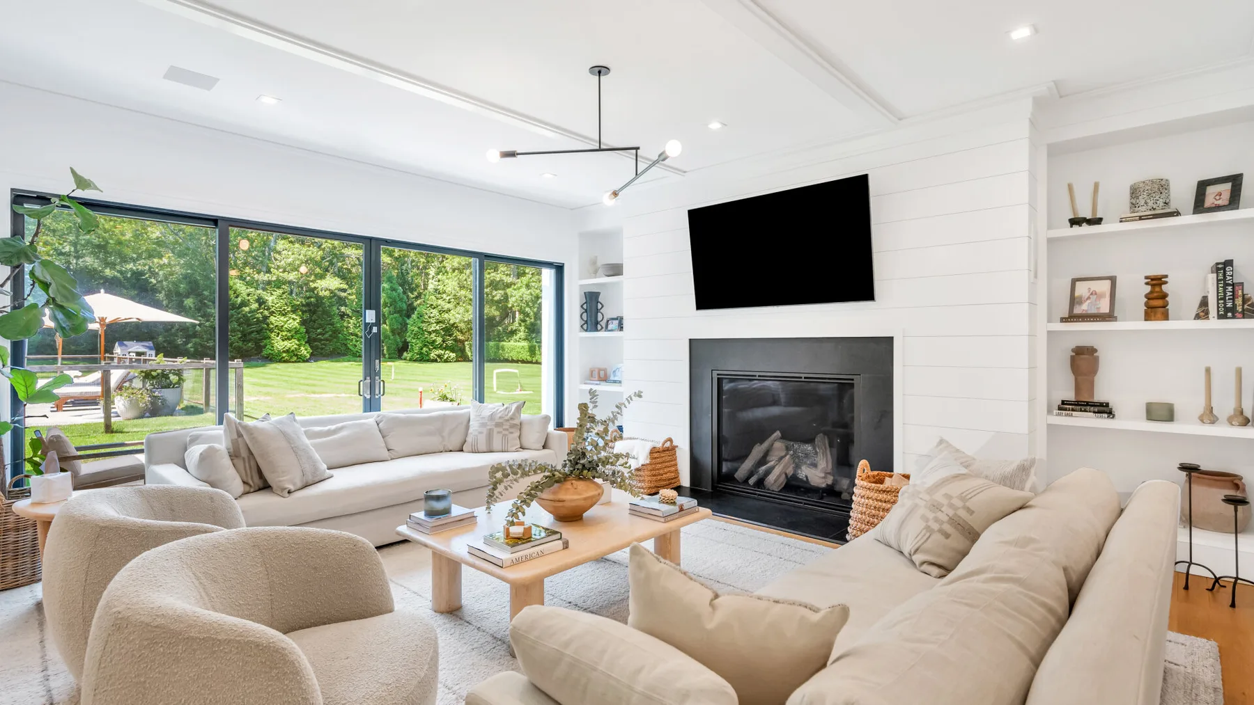 A bright living room with seating arranged around a fireplace and television.