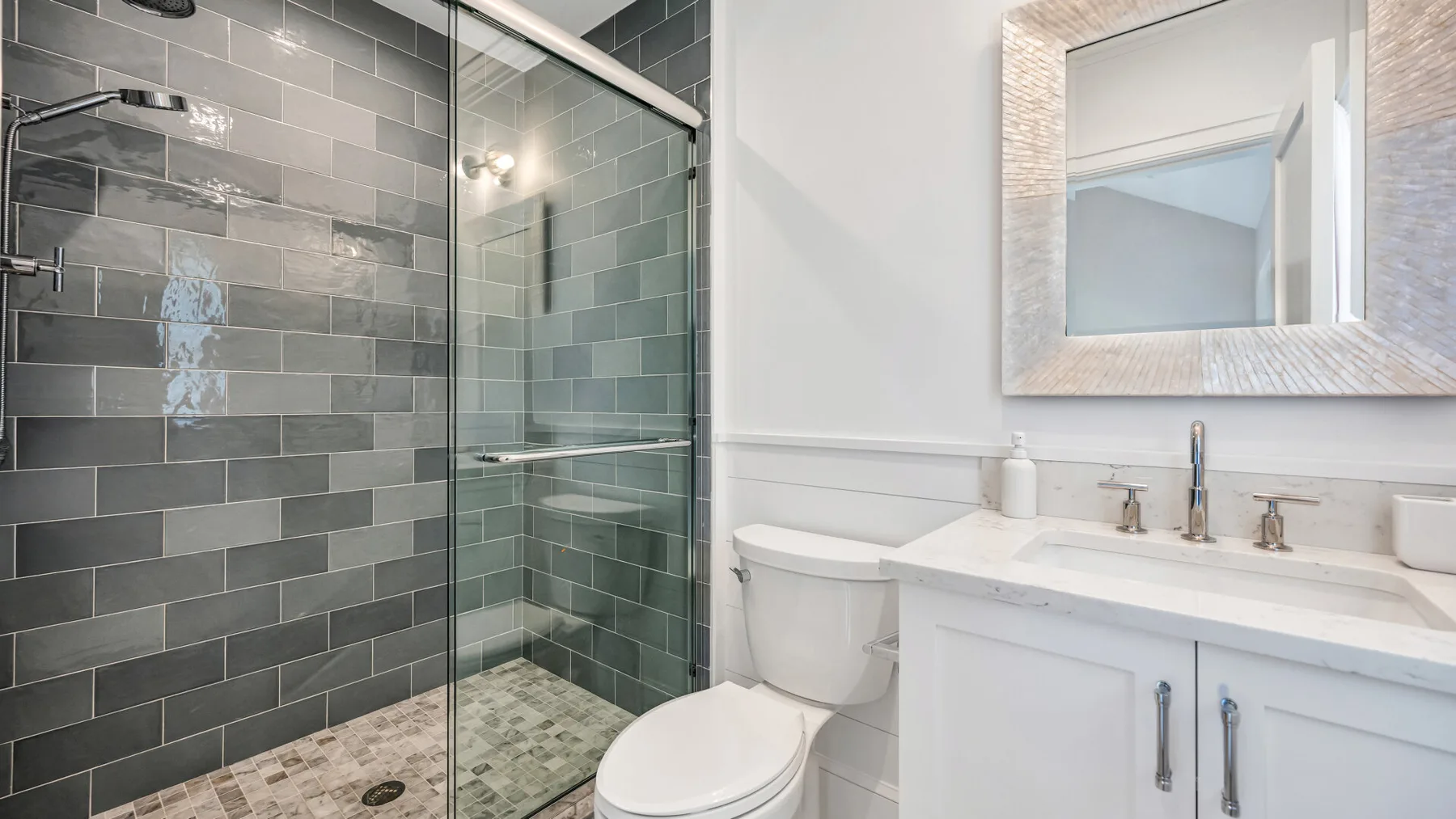 Un baño con ducha de vidrio, inodoro y tocador blanco.