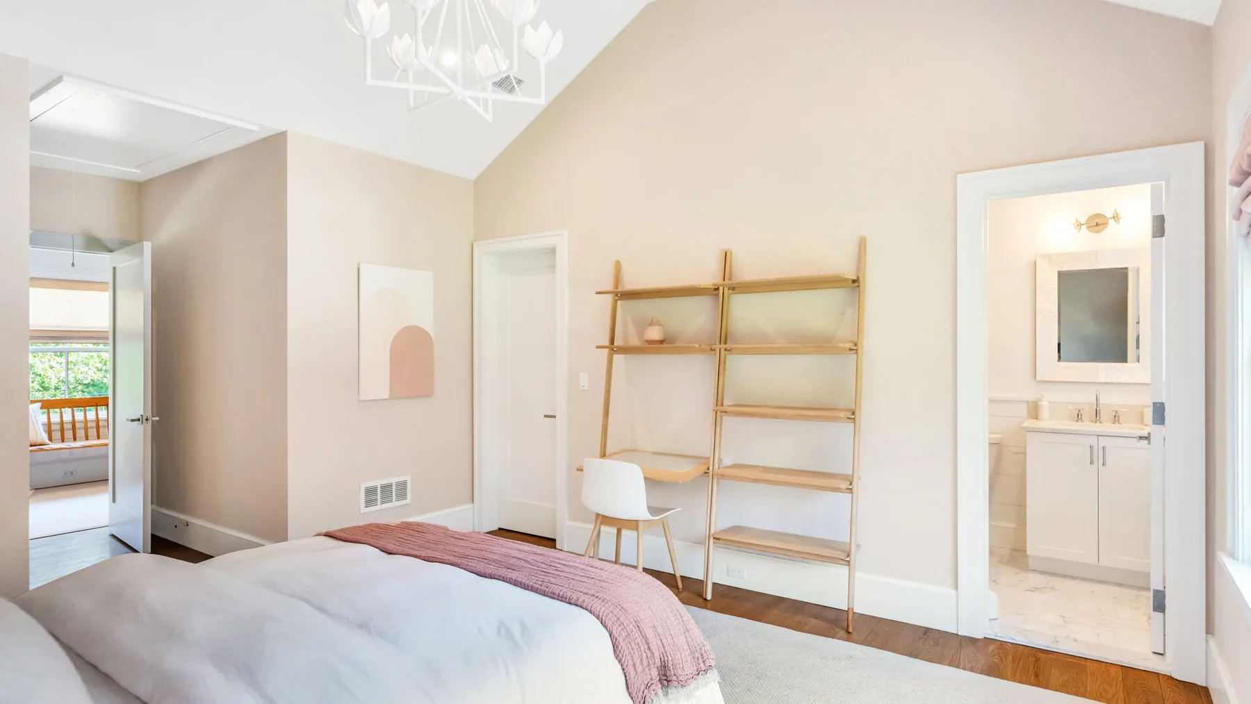 Un dormitorio luminoso con una cama, un escritorio y estantes abiertos.