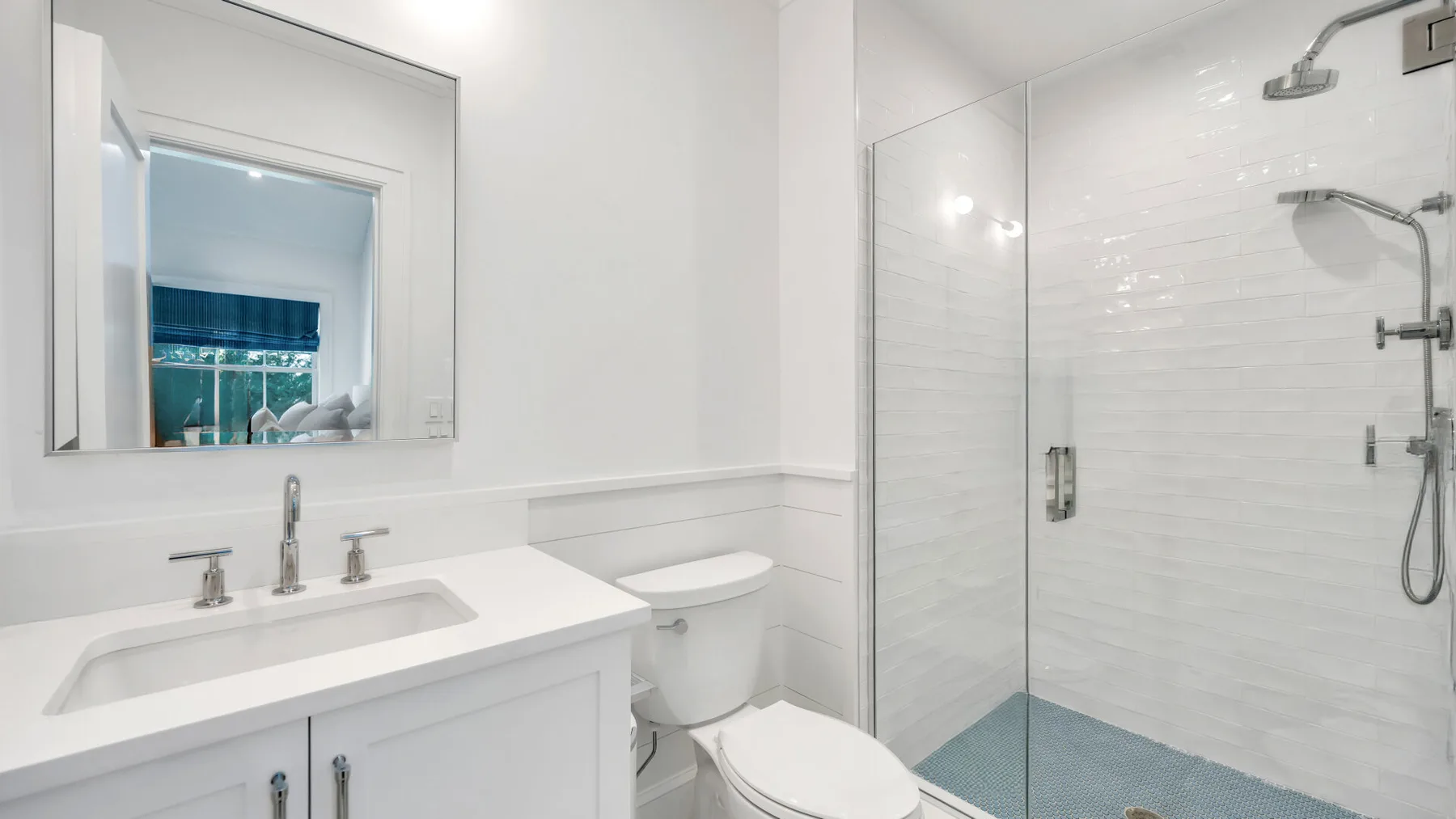 Un baño luminoso con lavabo, inodoro y ducha con mampara de vidrio.
