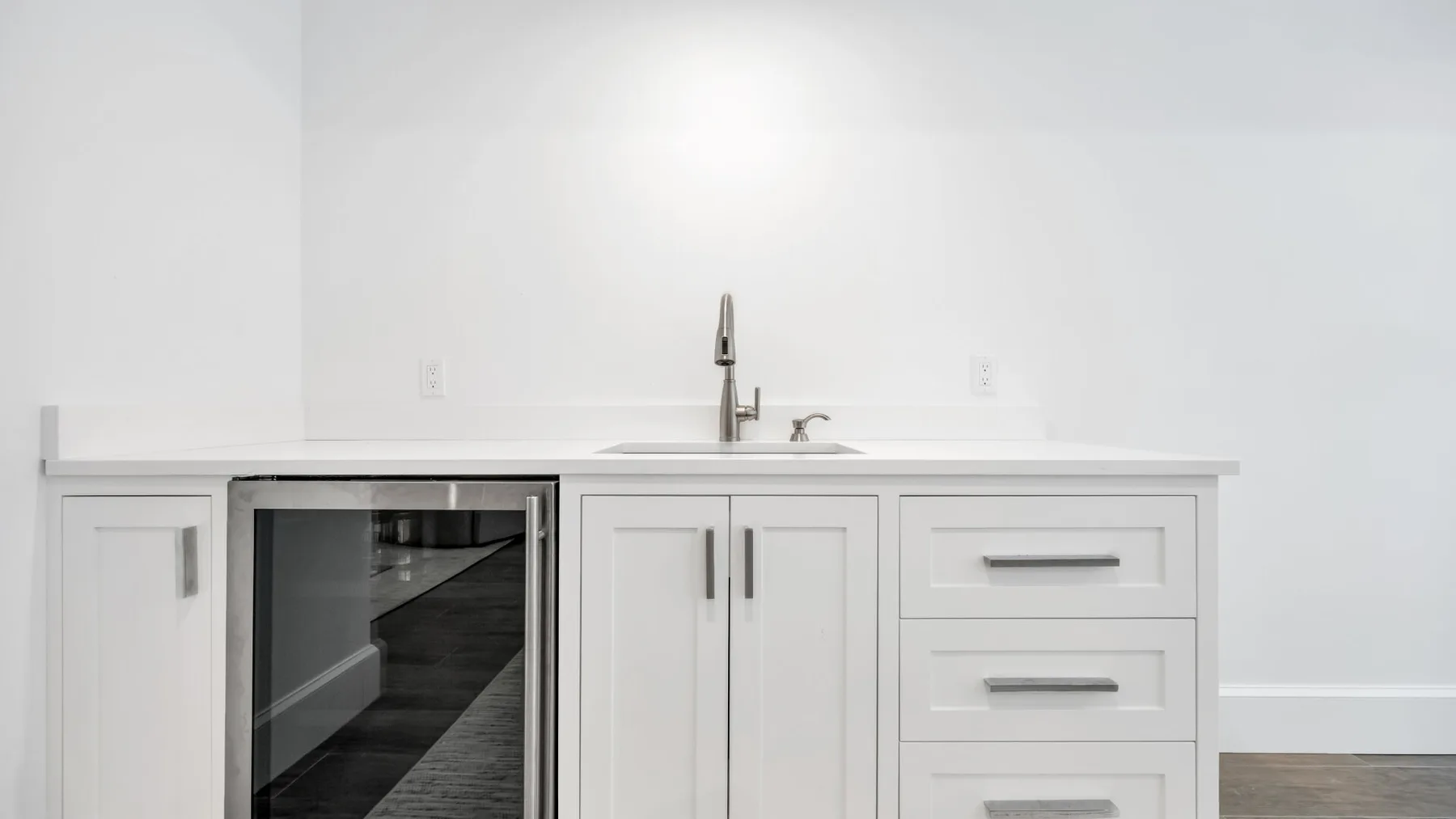 Un tocador de baño blanco con lavabo, cajones y un armario con frente de vidrio.