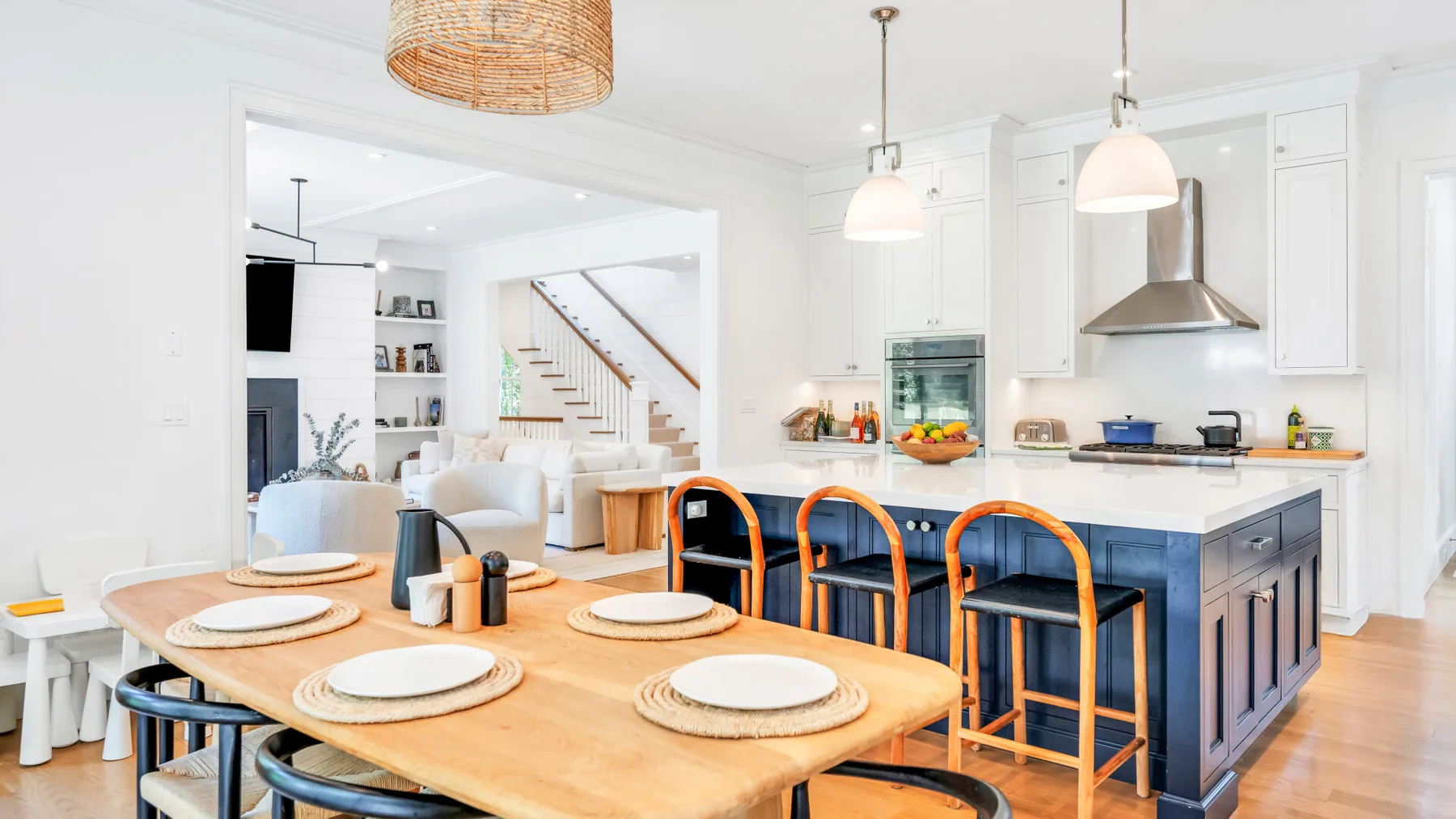 Cocina y comedor de planta abierta con una mesa de madera e isla azul.