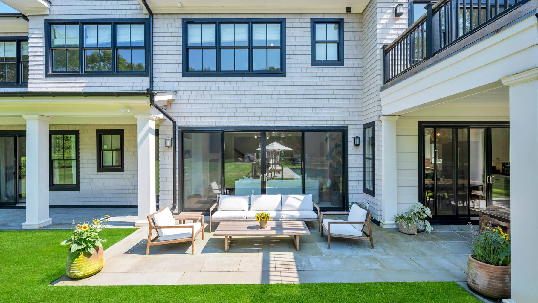 Un patio exterior pavimentado con asientos y una puerta corrediza de vidrio.
