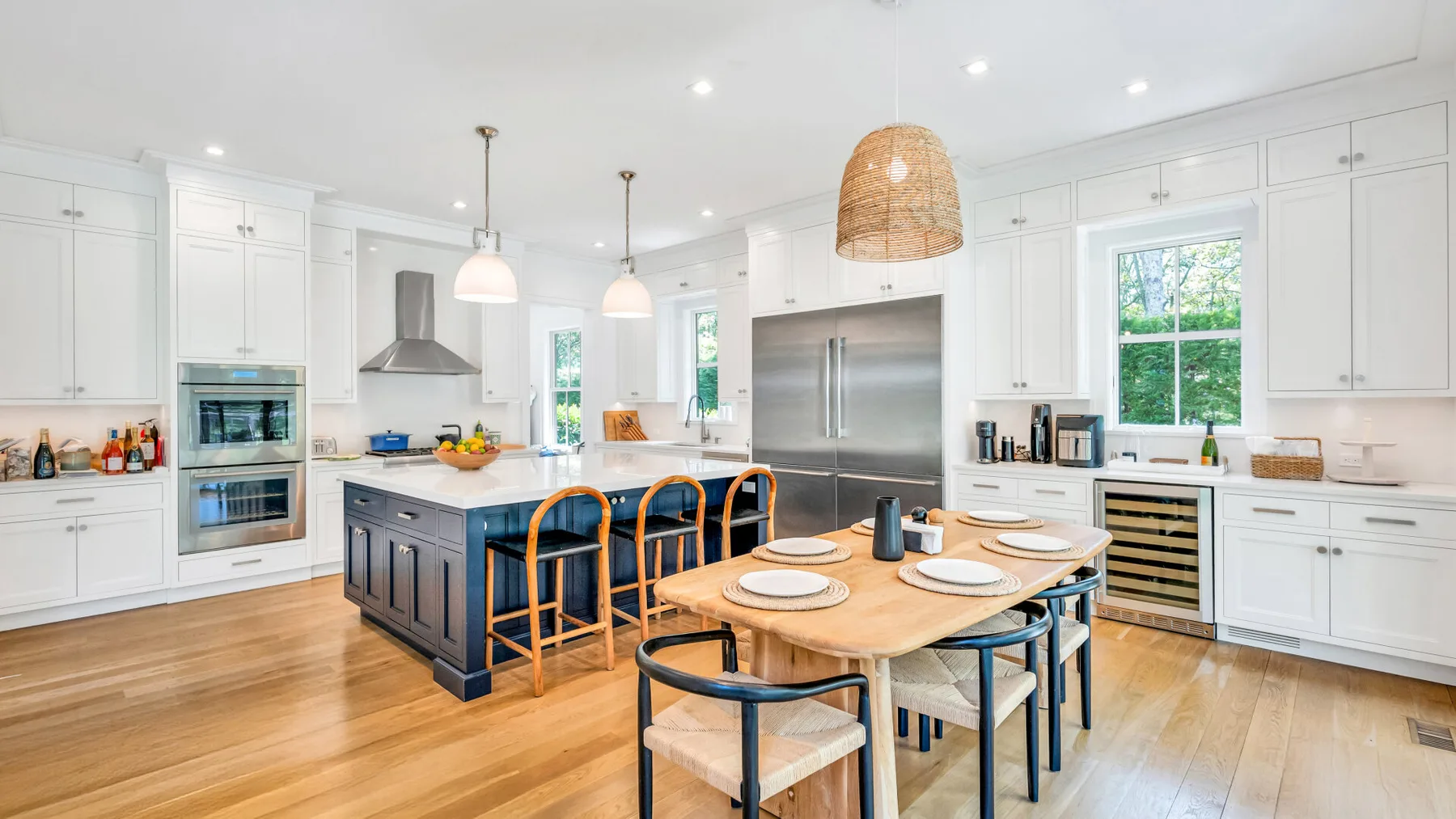 Una cocina luminosa con una isla amplia, mesa de comedor y gabinetes blancos.