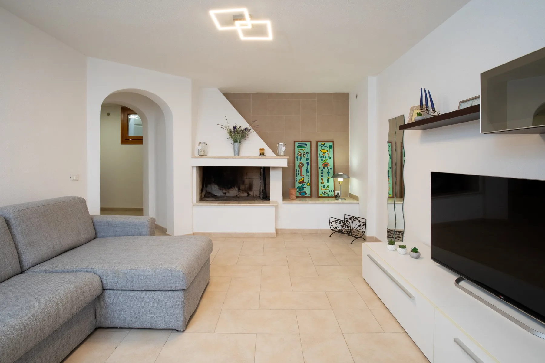 Una sala luminosa con asientos grises y un televisor.