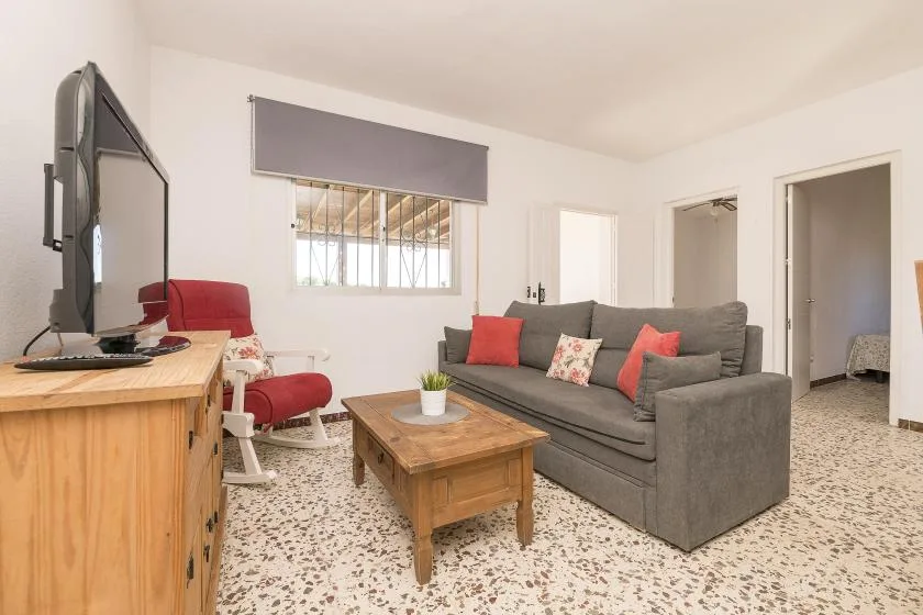 A living room with gray seating, a wooden coffee table, and a television.
