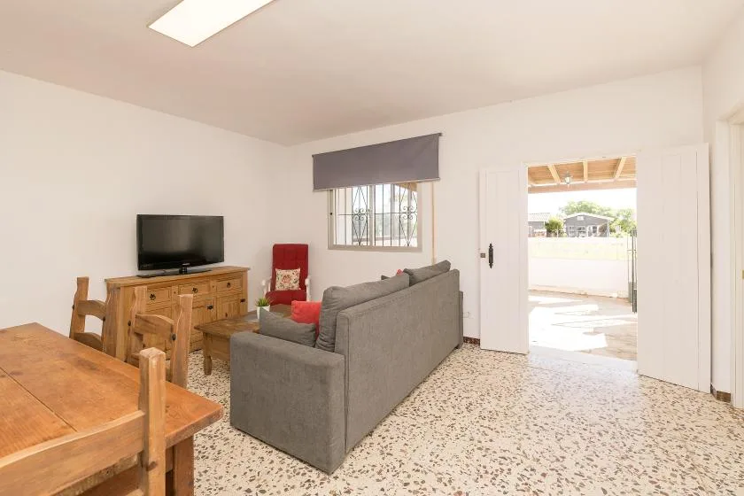 A living room with gray seating, a television, and an open doorway.