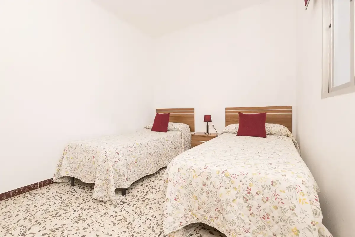 A bedroom with two beds dressed in floral-patterned bedding.