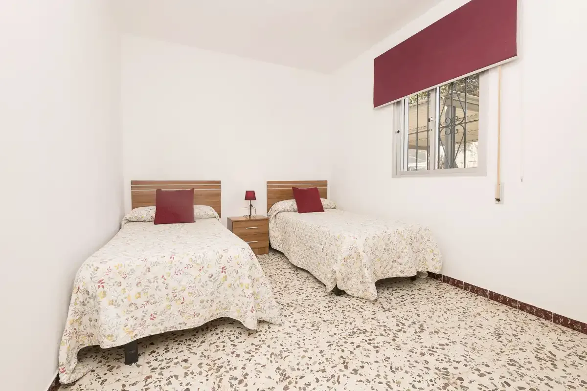 A bedroom with two single beds and a window.