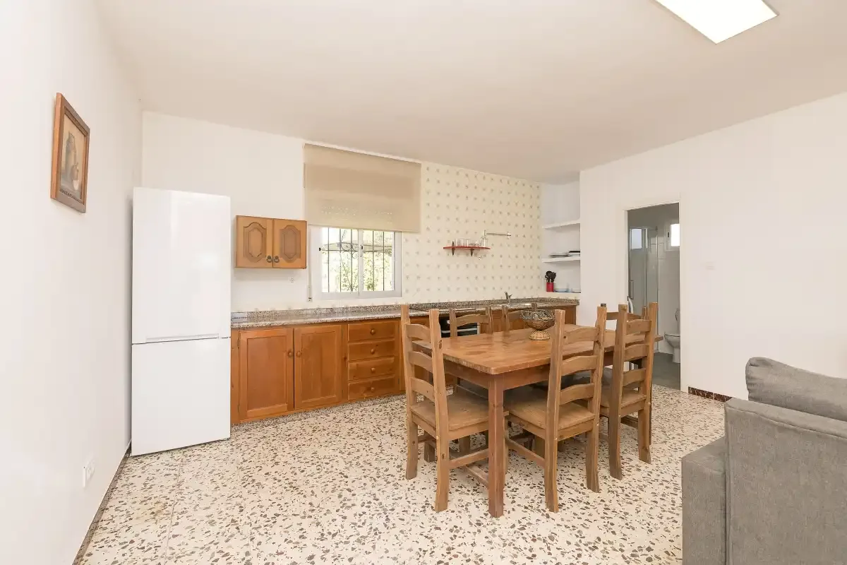 A kitchen and dining area with wooden cabinets, a table, and seating.