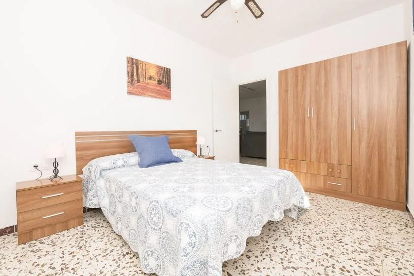 A bedroom with a double bed, wooden headboard, and large wardrobe.