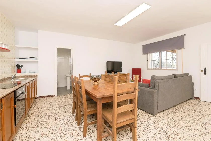 An open-plan dining and living area has a wooden table and gray seating.