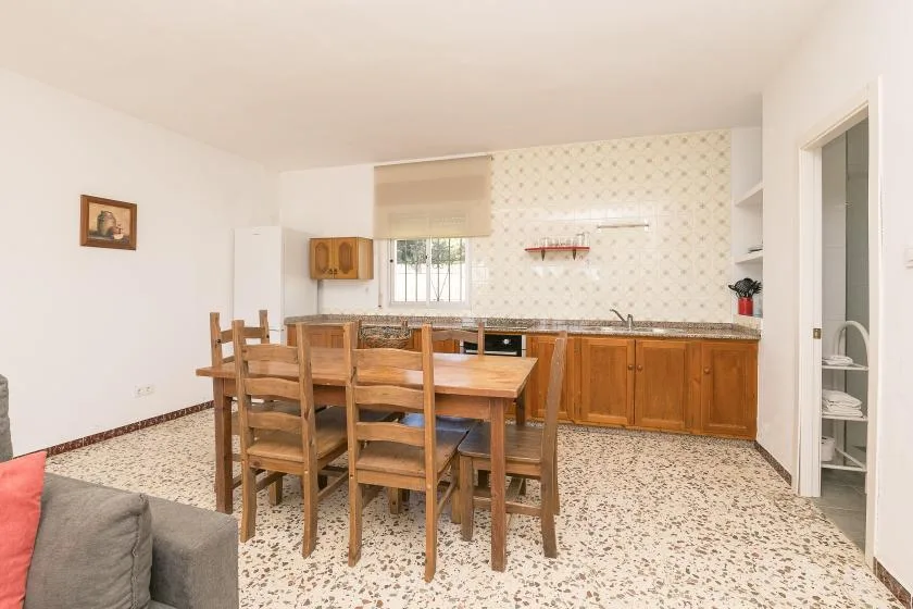 A dining area with a wooden table and chairs beside a kitchen.