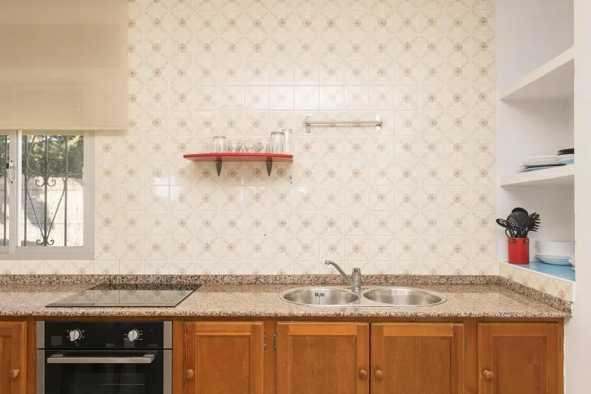 A kitchen counter with a sink, stovetop, and wooden cabinets.