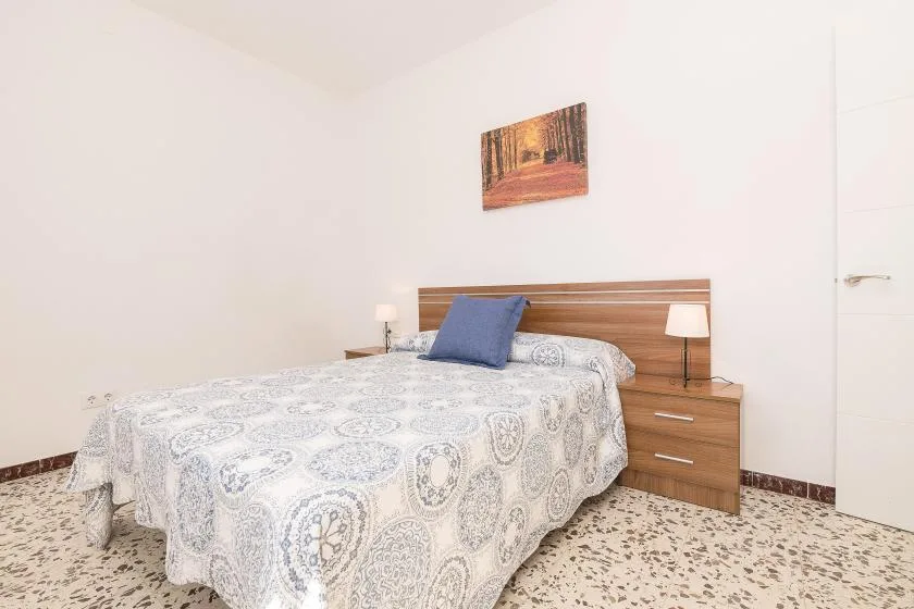 A bedroom with a double bed, patterned bedding, and bedside tables.