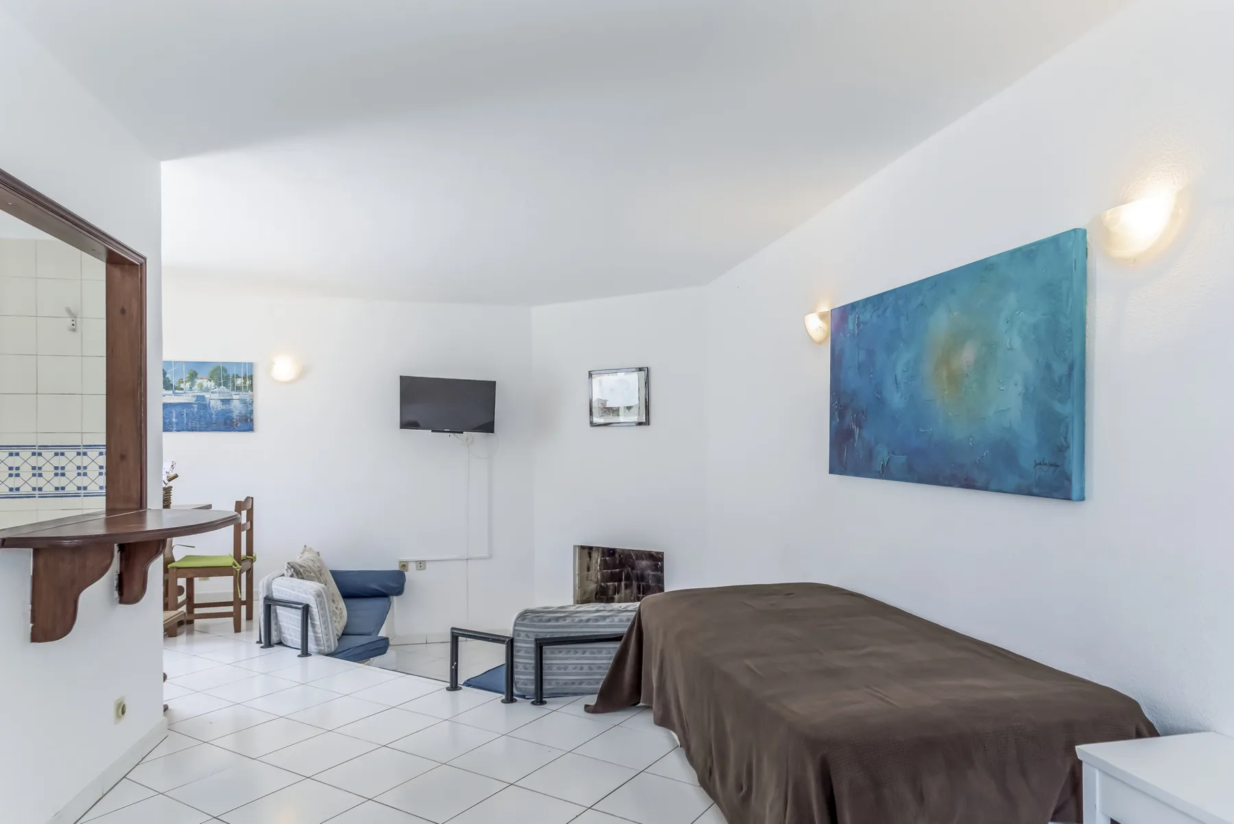 A bedroom with a bed, seating area, and television.