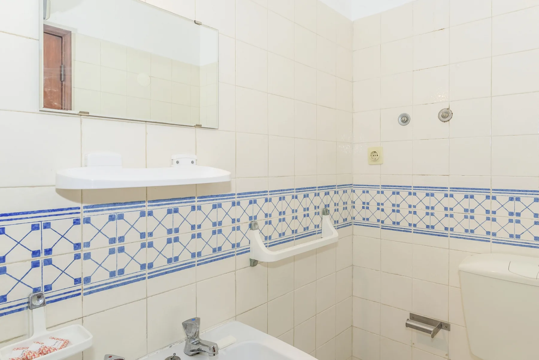 A tiled bathroom with a wall-mounted sink and bathtub.
