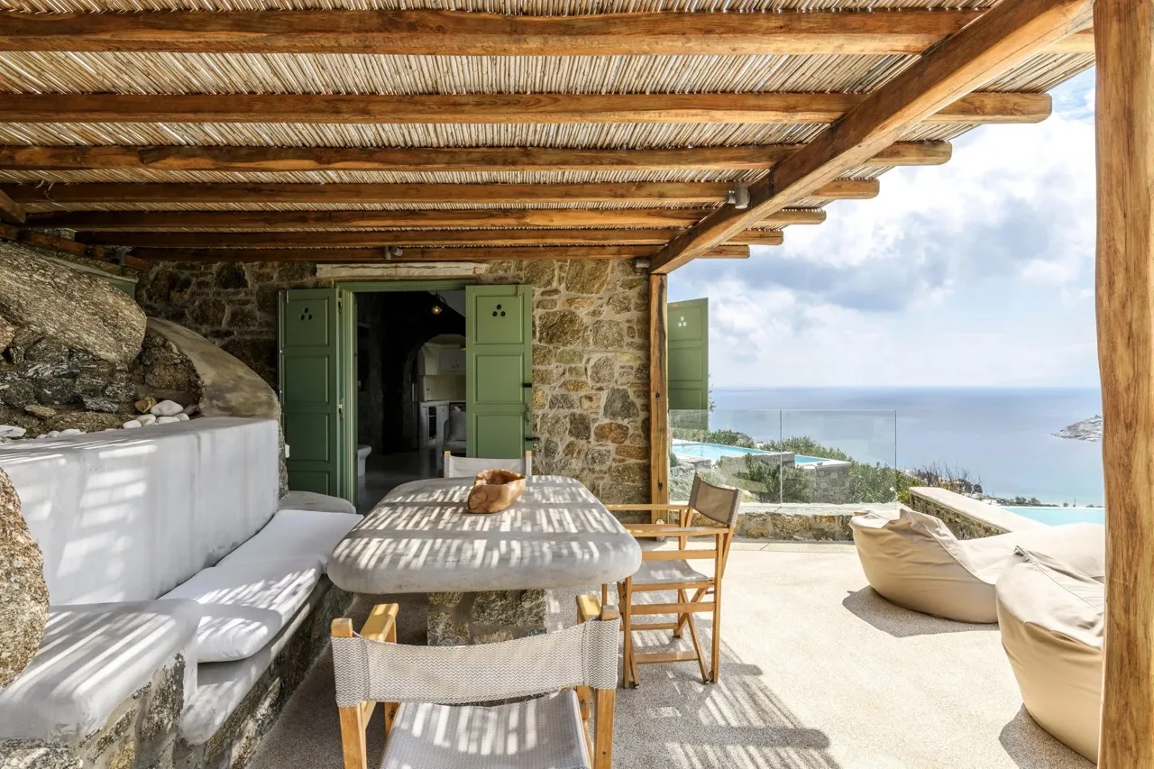 A shaded outdoor dining area opens onto a terrace with sea views.