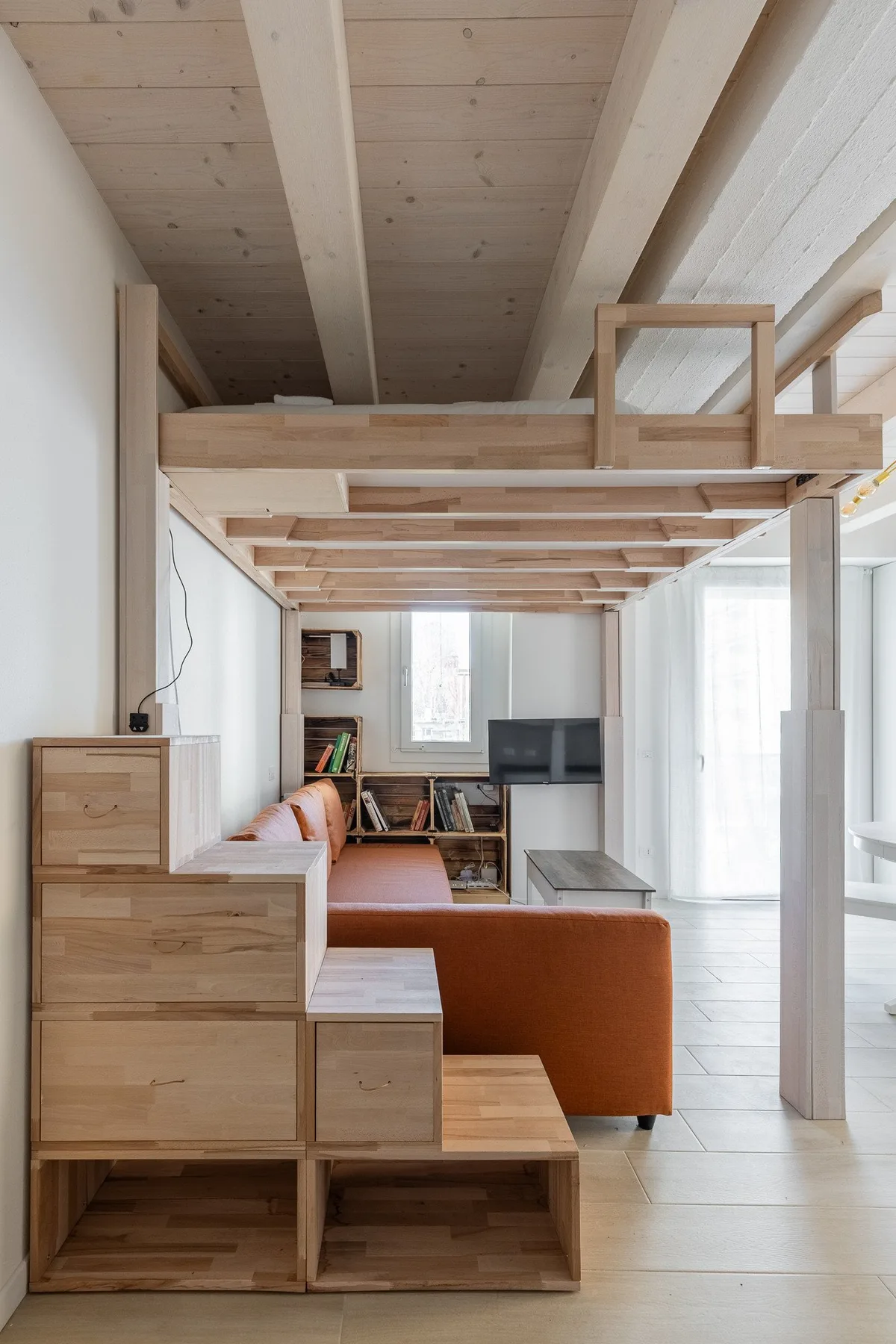 Una sala compacta con asientos de madera integrados bajo una plataforma elevada.