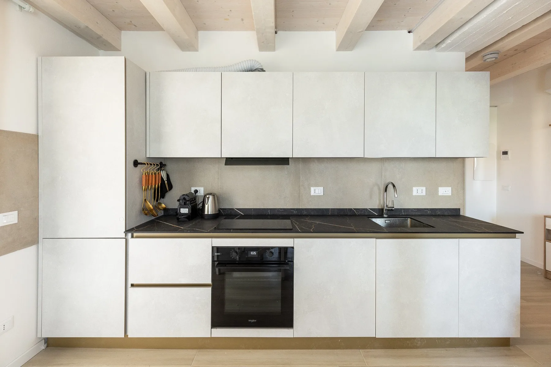 Una cocina moderna con gabinetes blancos, una encimera oscura y un horno.