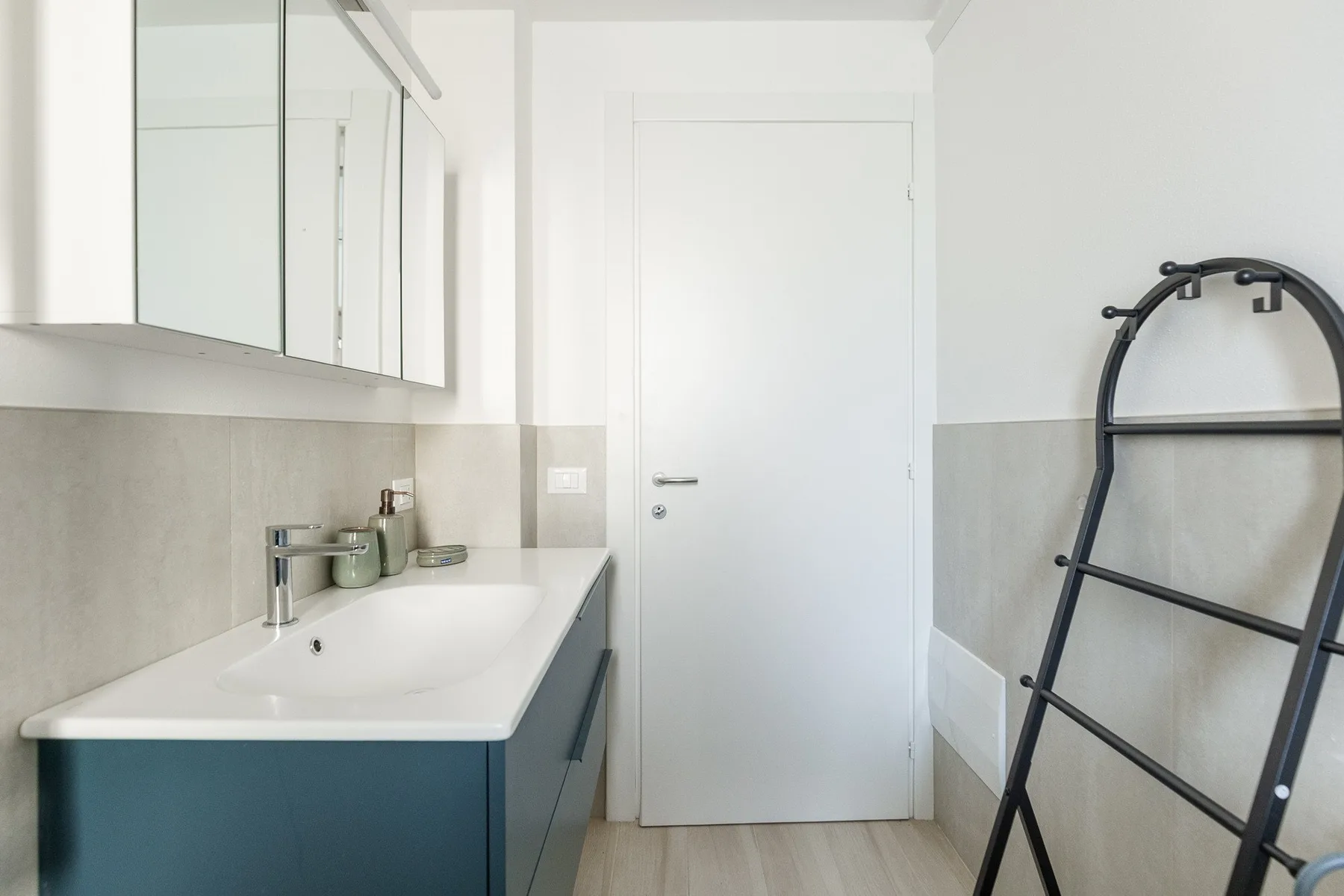 Un baño luminoso con lavabo, armarios con espejo y un toallero.