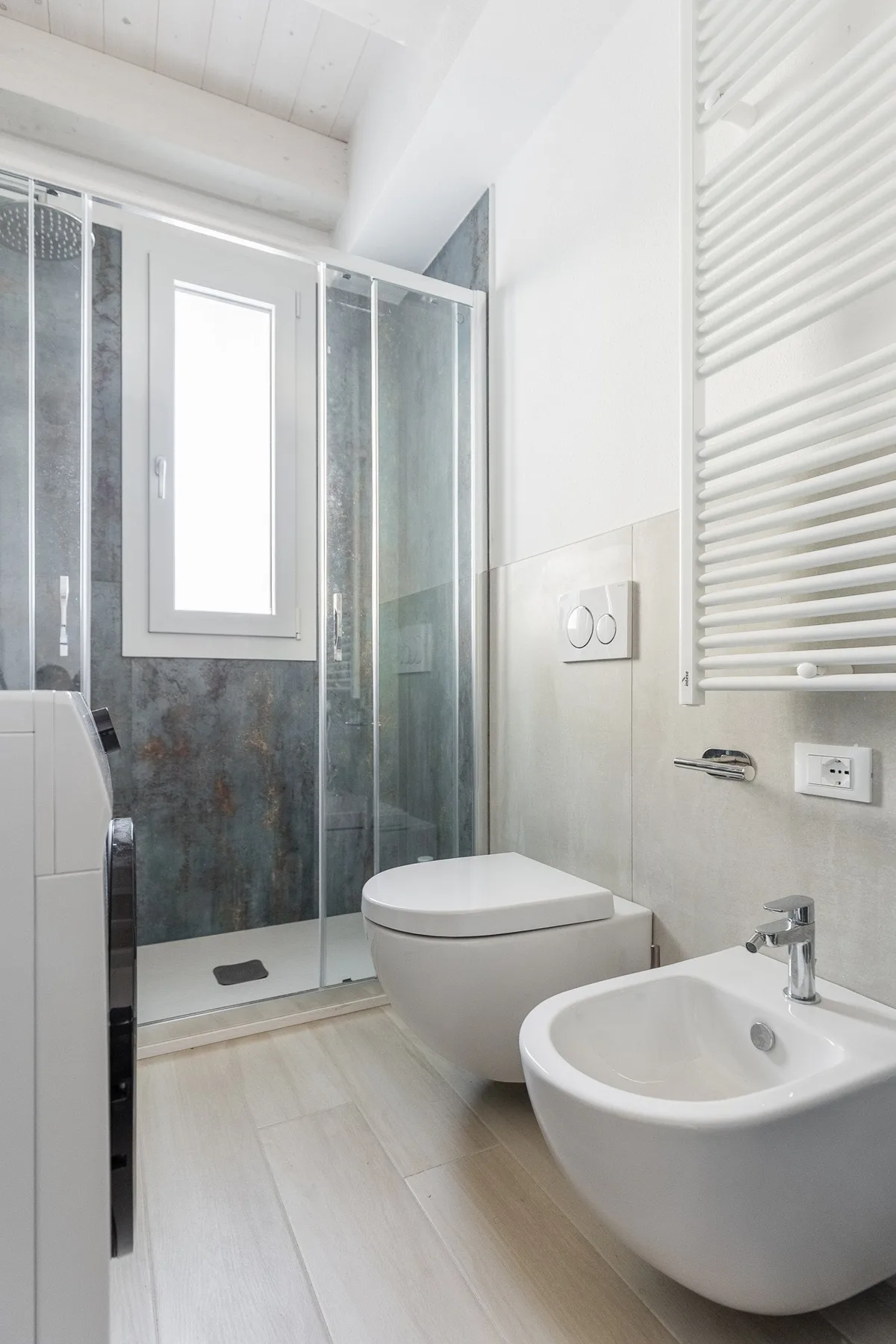 Un baño luminoso con ducha de vidrio, inodoro y bidé.