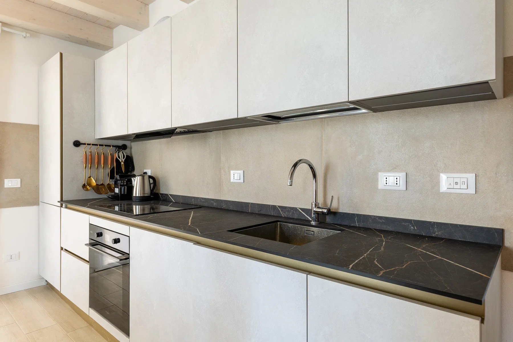 Una cocina moderna con gabinetes blancos, una encimera oscura y un fregadero.