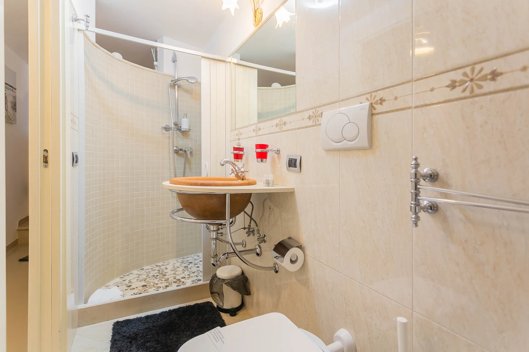 A tiled bathroom with a glass shower, sink, and toilet.