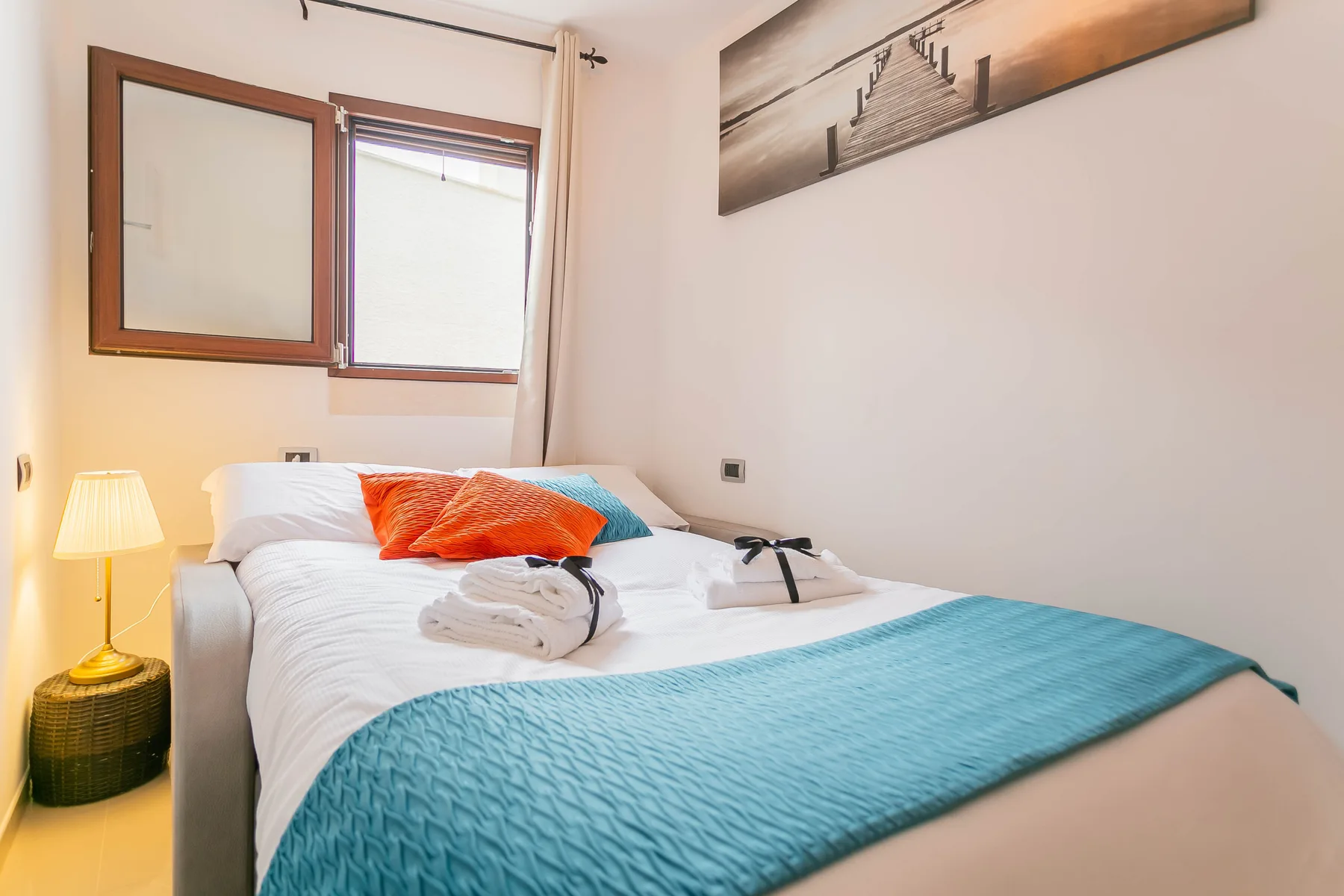 A bedroom with a neatly made bed and a turquoise blanket.