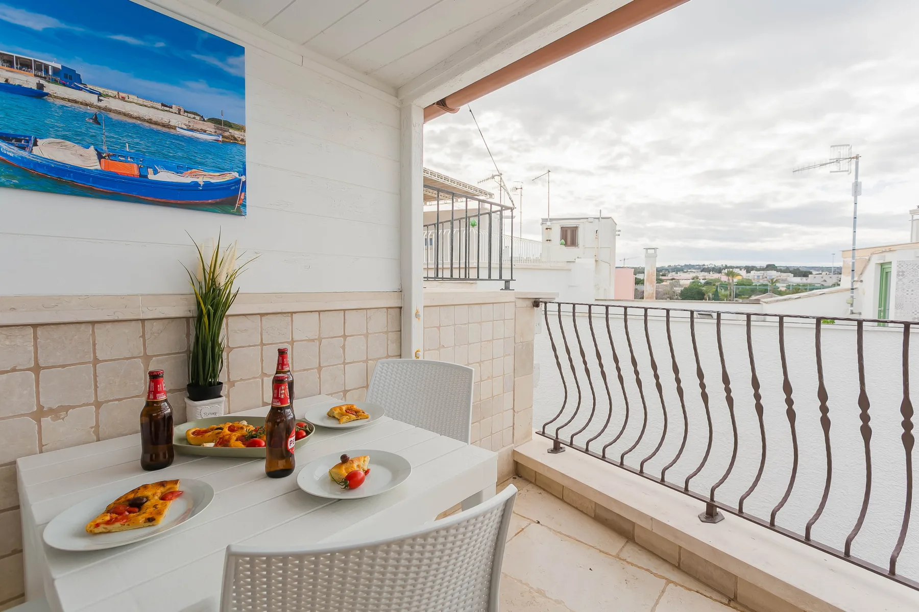A covered balcony dining area with a table and a view of nearby buildings.