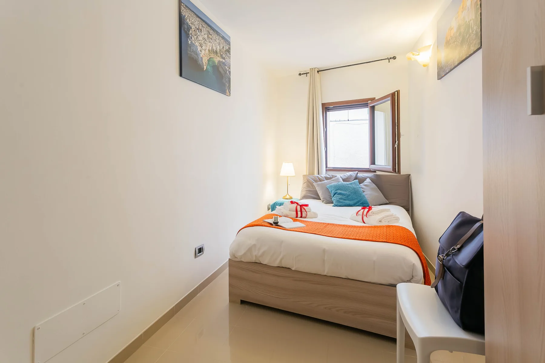A bedroom with a neatly made bed beneath a window.