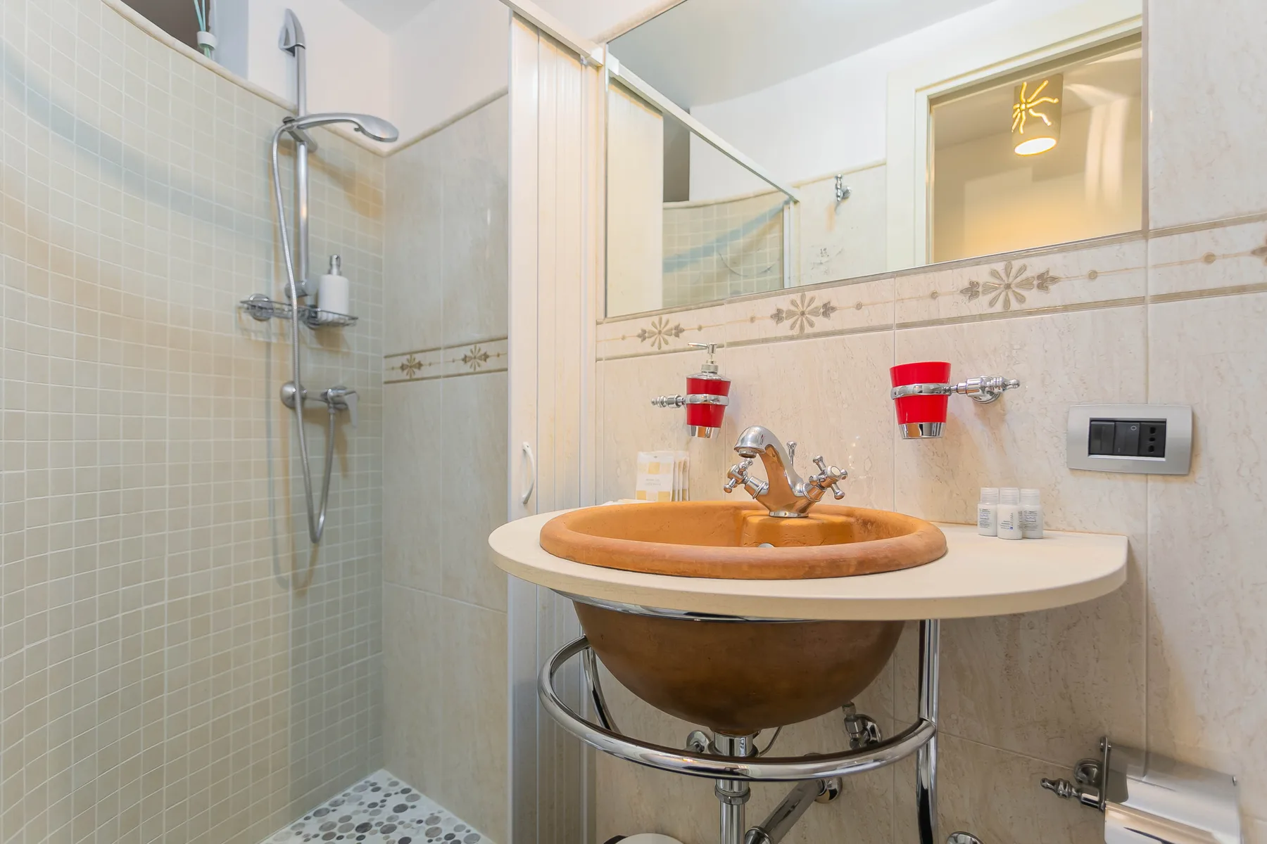A bathroom vanity with a round basin sits beside a tiled shower.