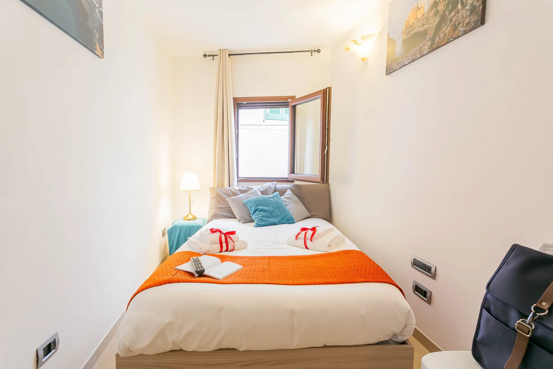 A bedroom with a neatly made bed and an open window.