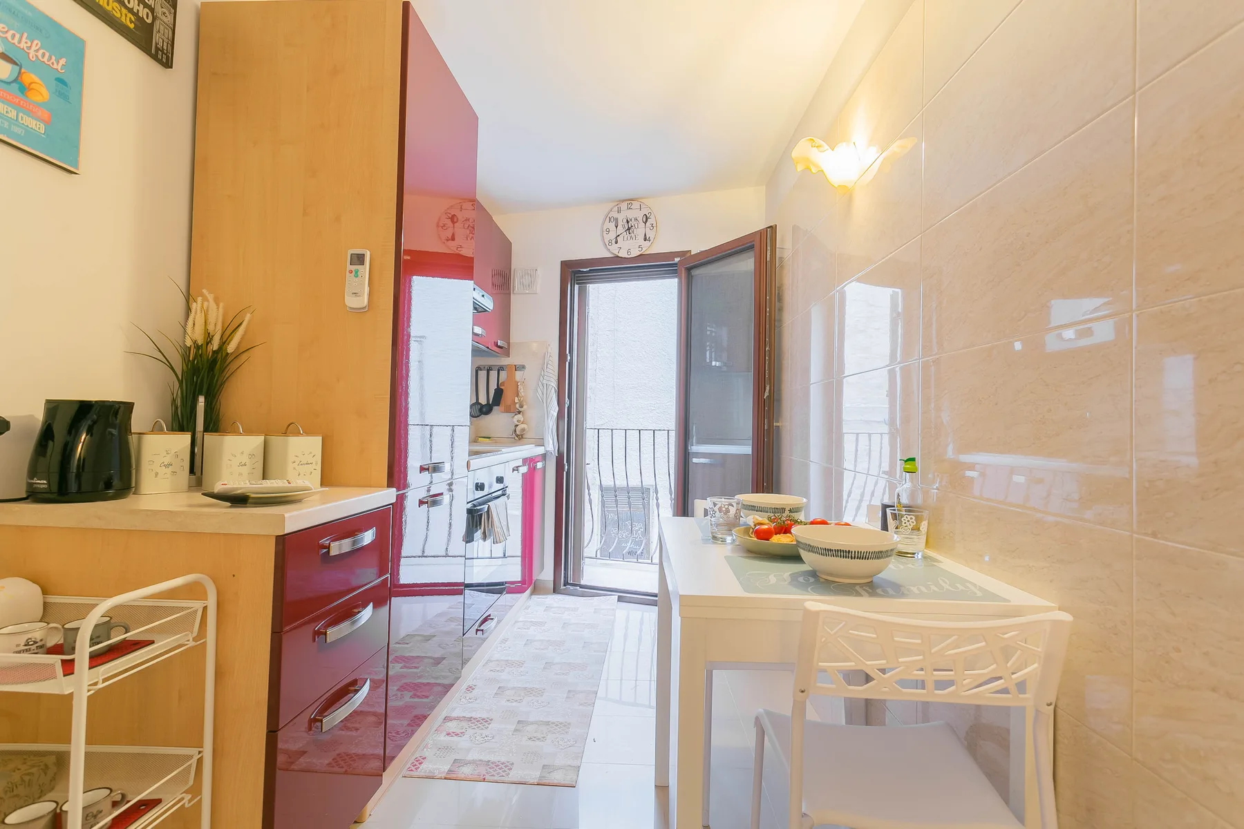 A narrow kitchen and dining area opens onto a balcony through glass doors.