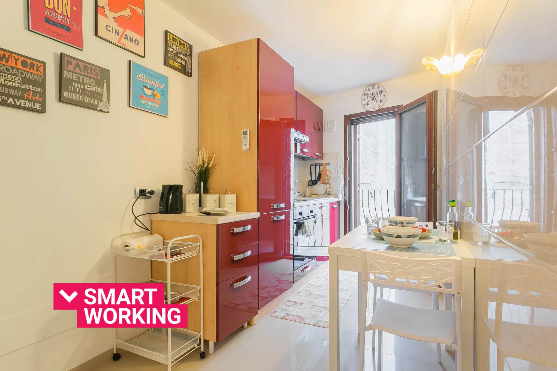 A bright kitchen with red cabinets, a dining table, and glass doors.