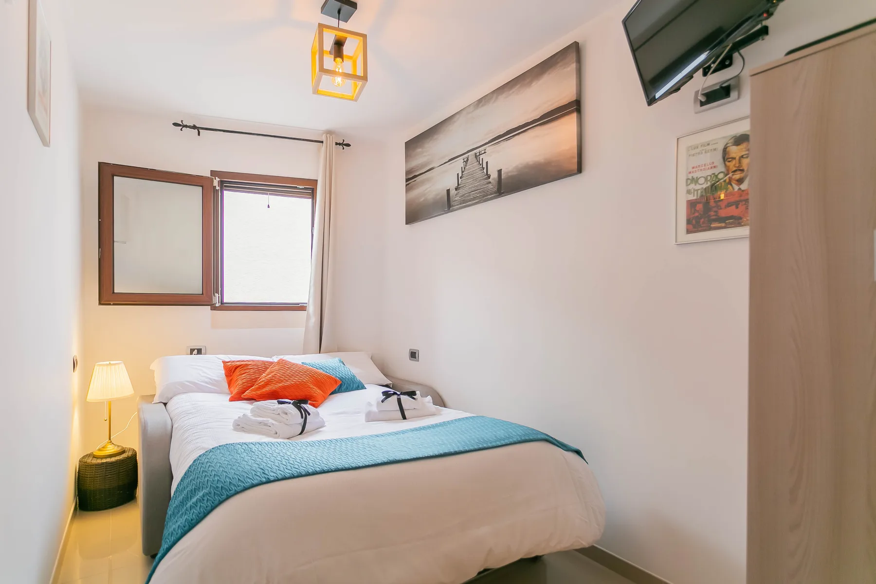 A bedroom with a neatly made bed and a window.