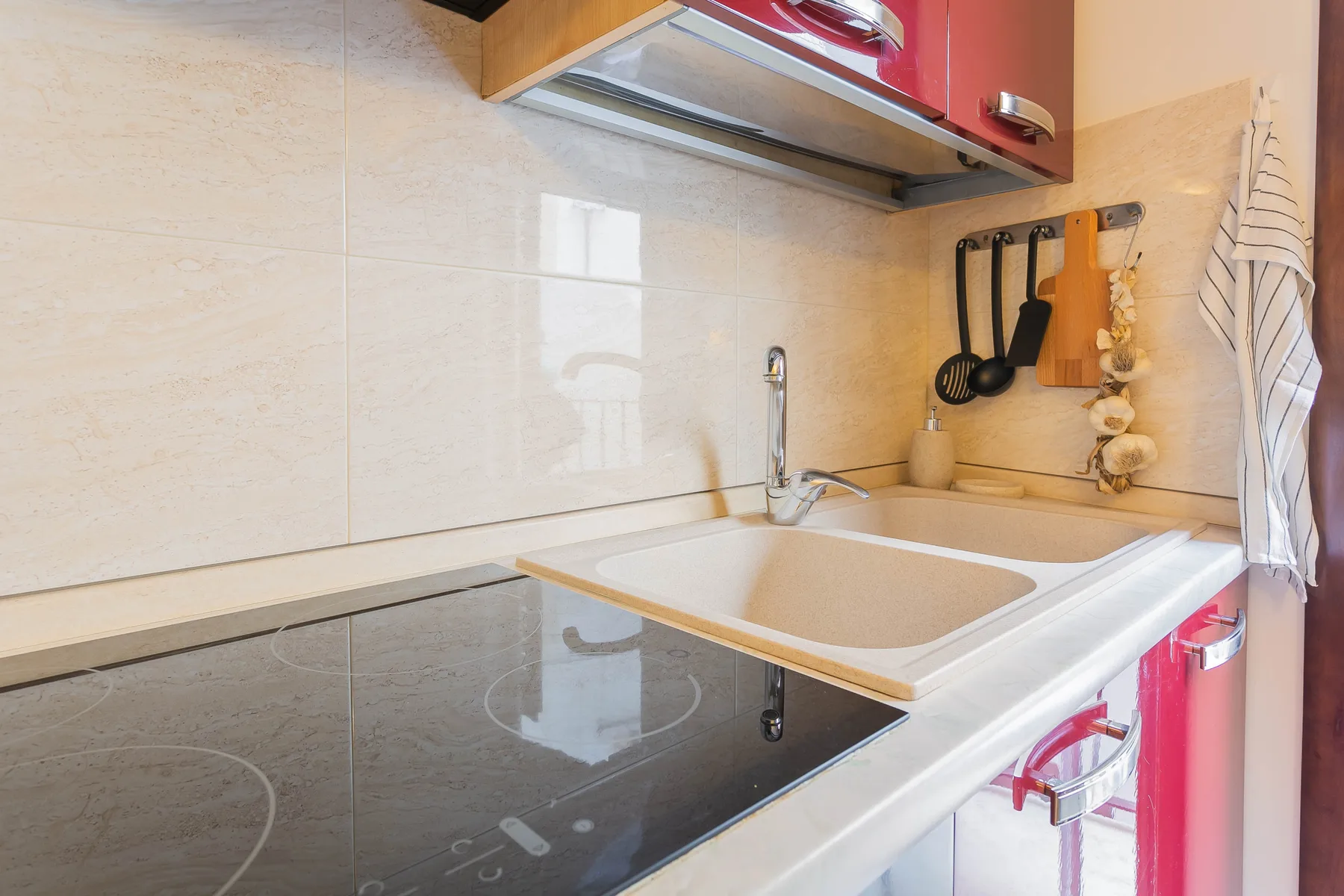 A kitchen countertop with a sink and black glass cooktop.