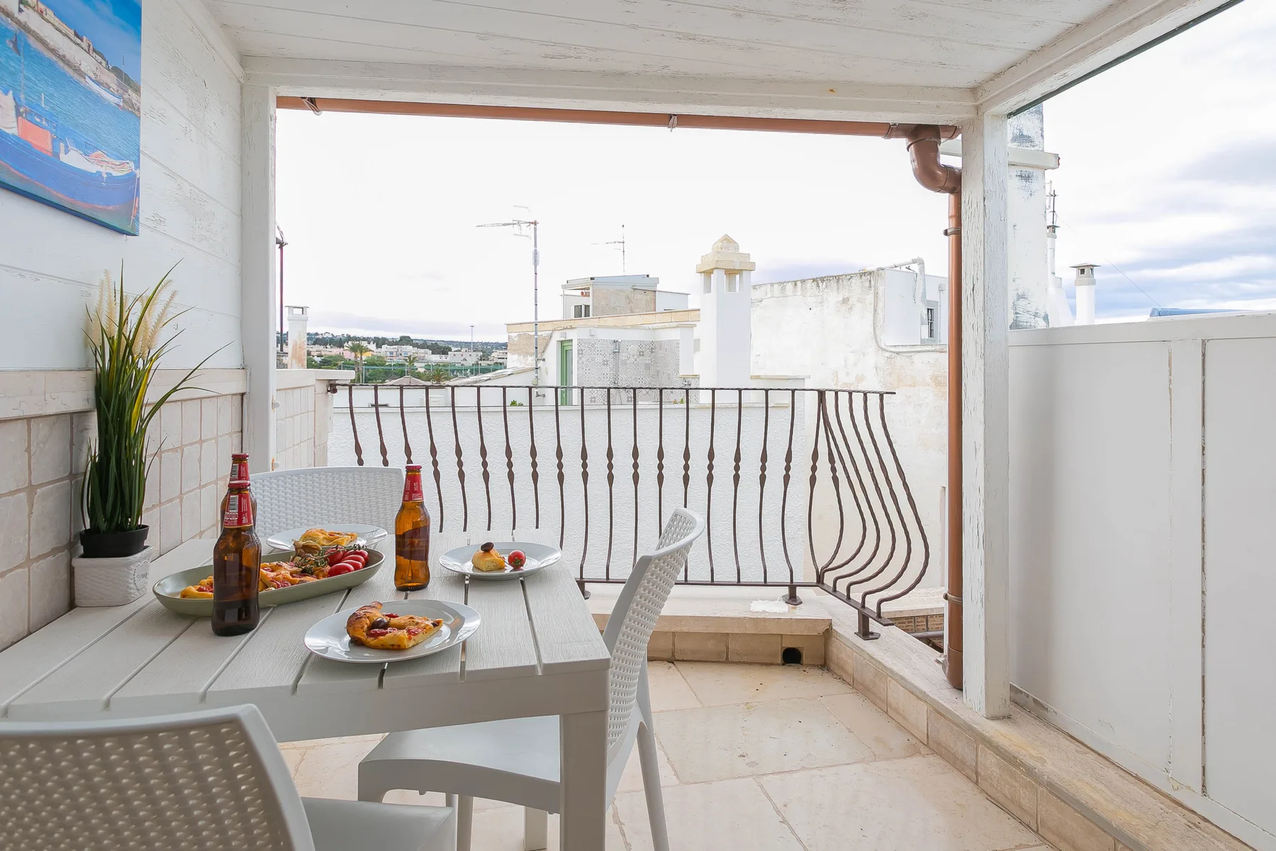 A covered balcony with a dining table and views of nearby rooftops.