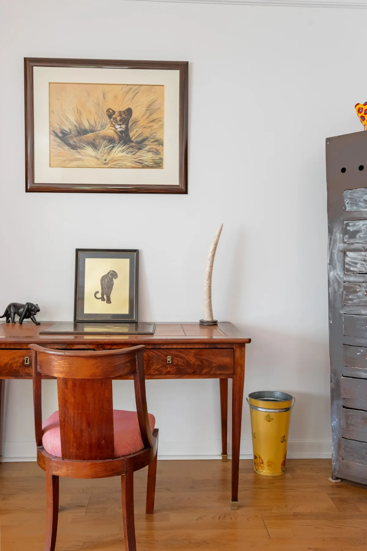 Un escritorio y una silla de madera están bajo cuadros de animales.