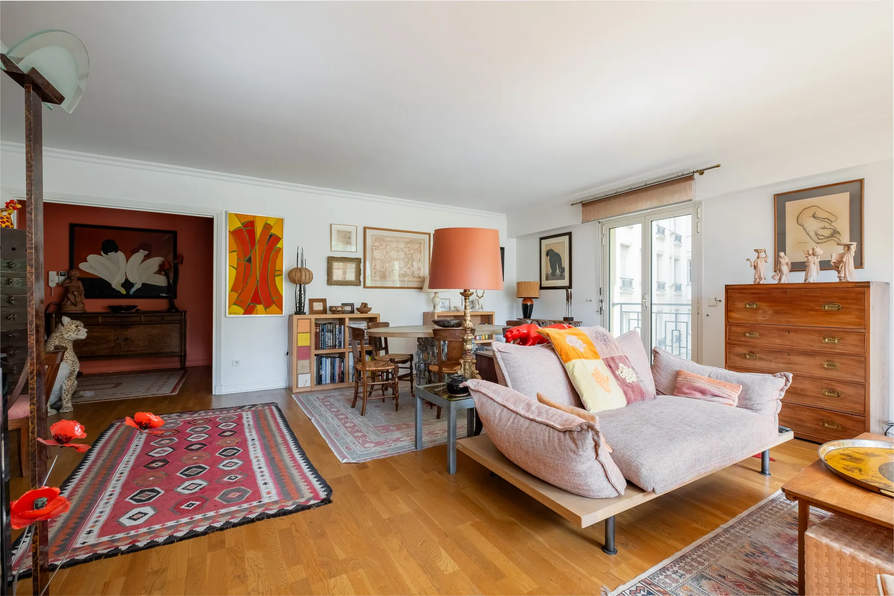 A bright living room with seating, a bookshelf, and large windows.