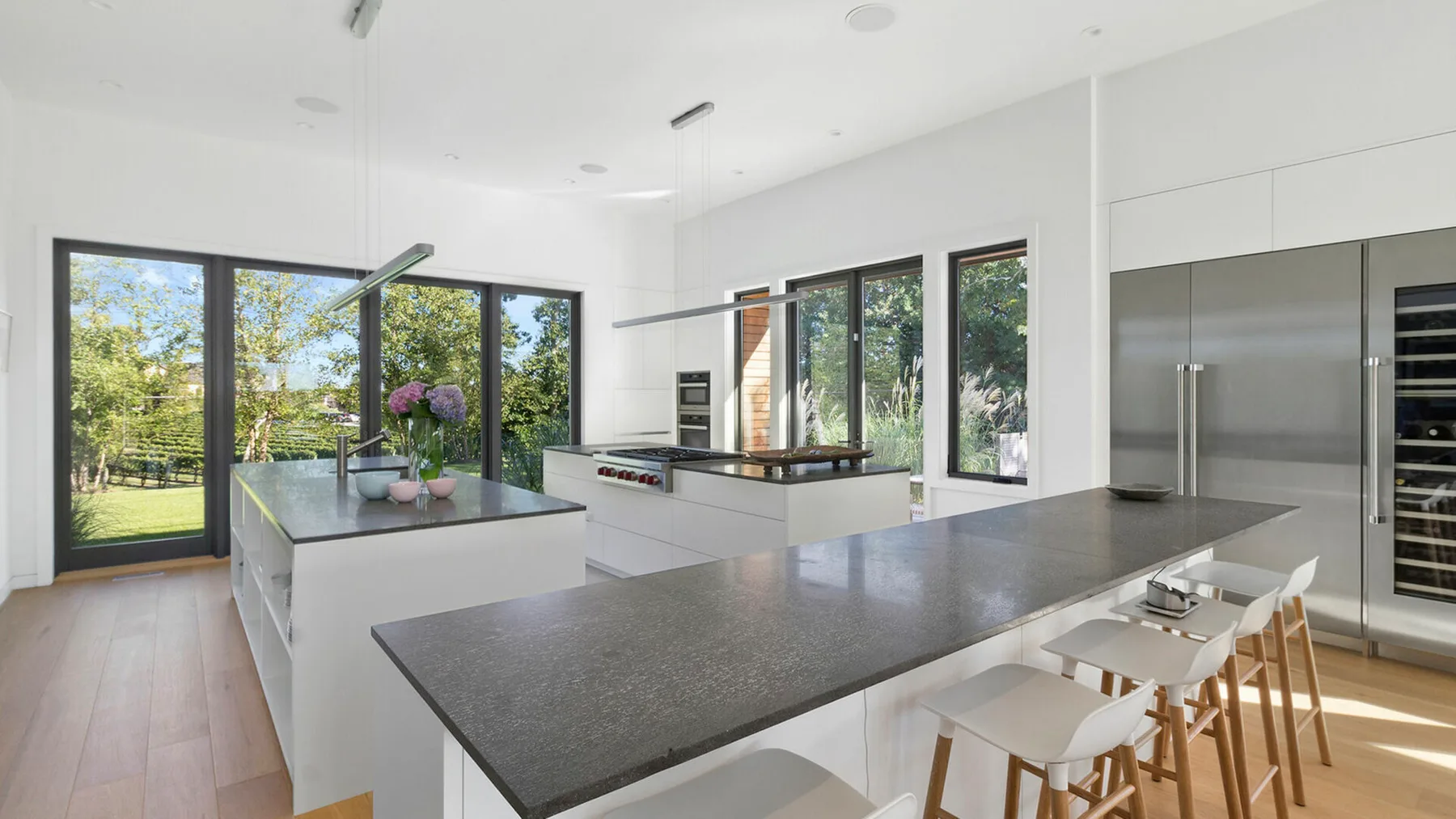 Una cocina moderna y luminosa con una amplia isla y grandes ventanas con vistas a la vegetación.